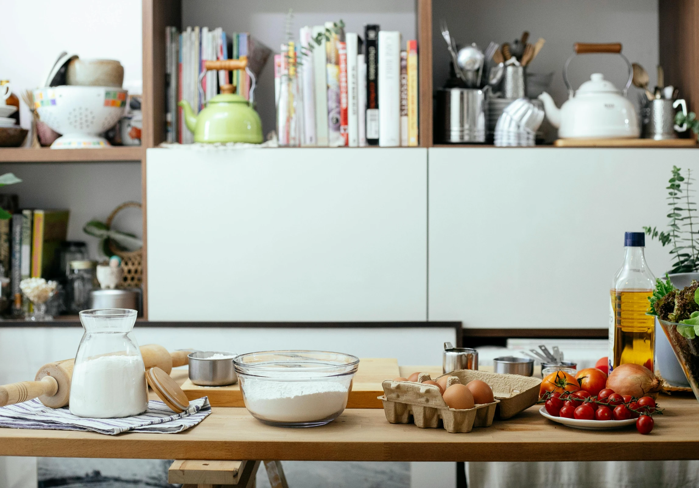 a wooden table topped with bowls of food, a still life, trending on pexels, process art, short bookshelf, baking cookies, background image, on kitchen table