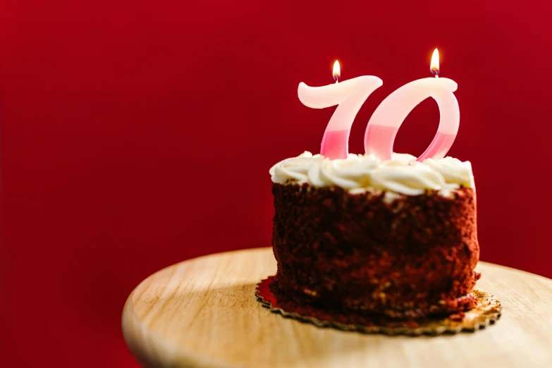 a birthday cake with a lit candle on top of it, pexels, photorealism, year 1 9 7 0, crimson themed, 1 0, modelling