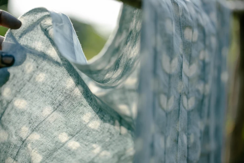 a person holding a piece of cloth on a clothes line, pale cyan and grey fabric, close up of iwakura lain, muted green, subtle pattern