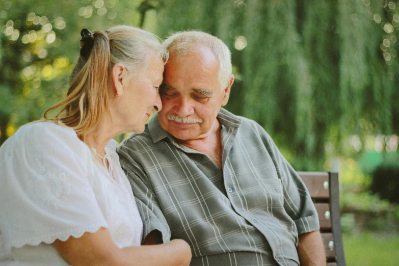 a man and a woman sitting on a bench, profile image, nursing home, lush surroundings, comforting