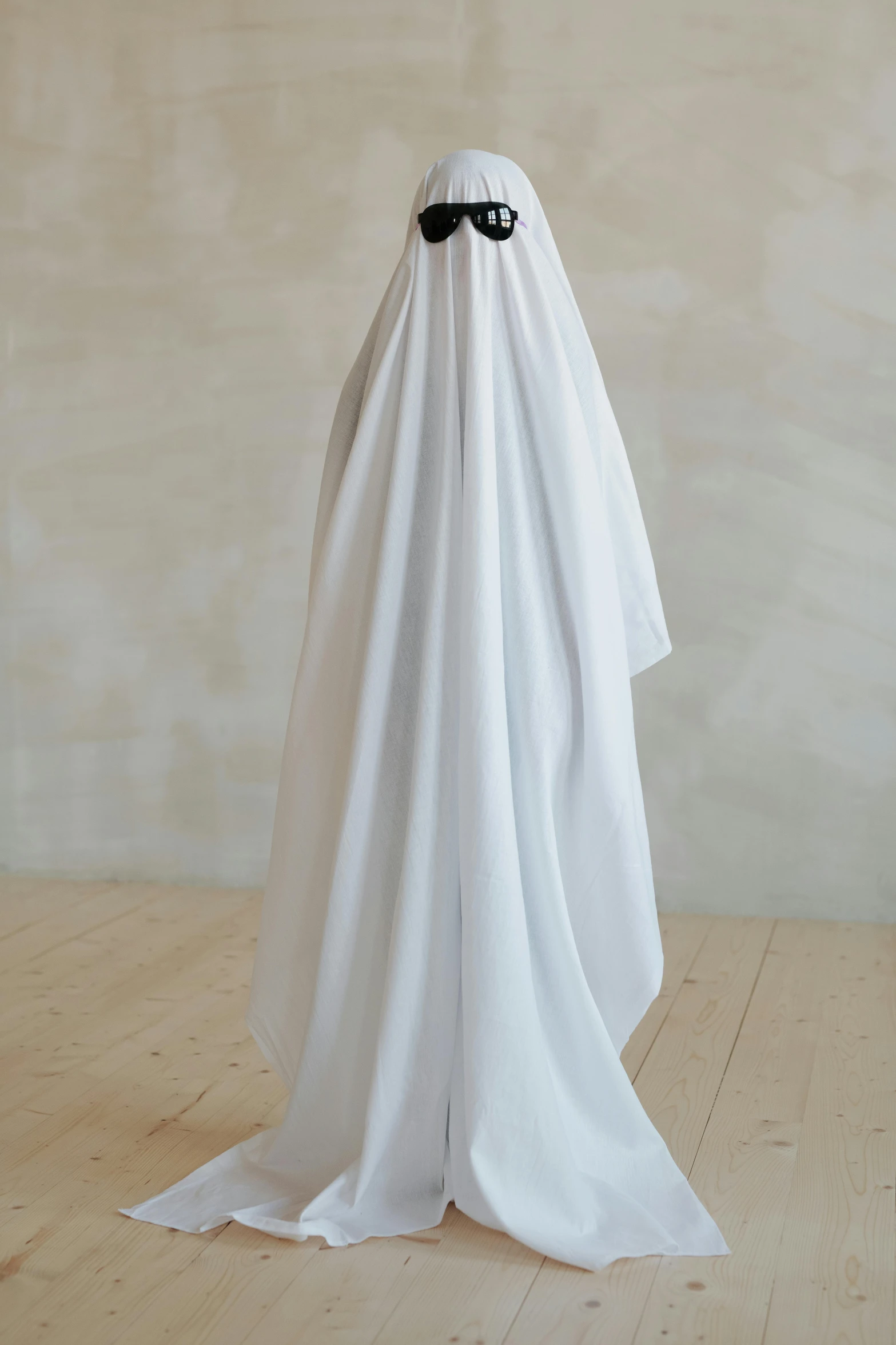 a white ghost sitting on top of a wooden floor, by Marina Abramović, unsplash, conceptual art, made of fabric, hijab, 3/4 front view, tuxedo