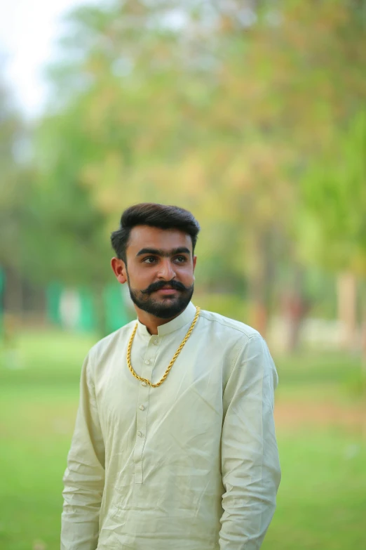 a man standing on top of a lush green field, a picture, samikshavad, wearing gold chain, headshot profile picture, at a park, ((portrait))