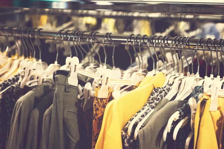 a rack of clothes in a clothing store, by Matija Jama, trending on pexels, renaissance, yellow clothes, 🦩🪐🐞👩🏻🦳, loosely cropped, retro effect