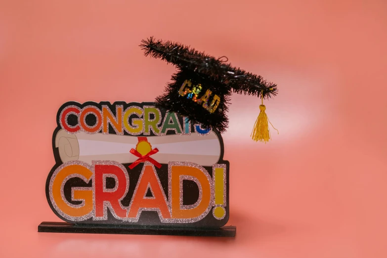 a sign that says congratulations grad with a graduation cap on top of it, a picture, by Bernie D’Andrea, pexels, papercraft, 3/4 front view, celebration costume, full product shot