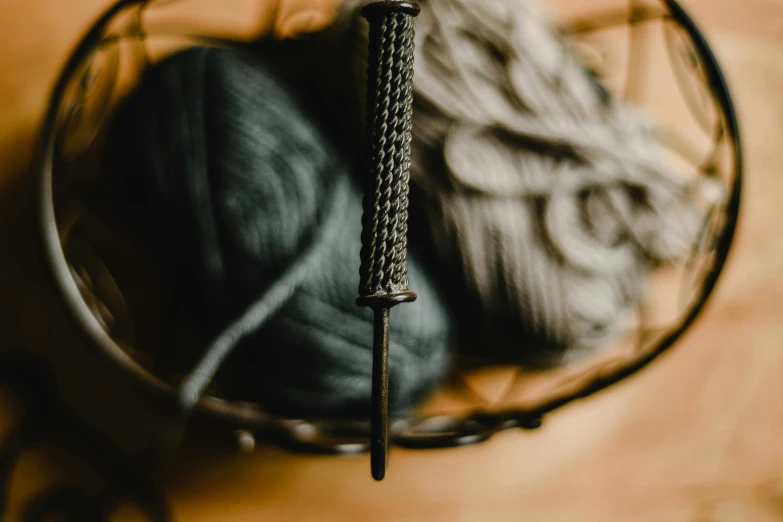 a close up of a ball of yarn in a basket, by Carey Morris, unsplash, arts and crafts movement, holds a black sword, promo image, chainmail, brown