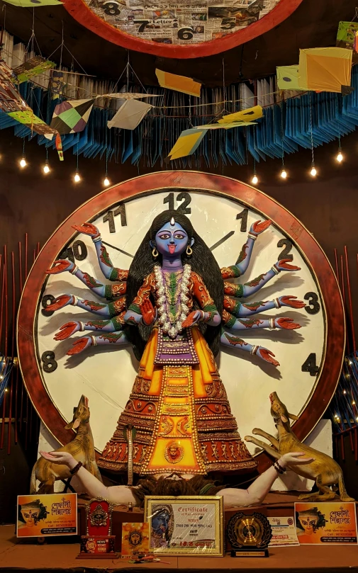 a large clock sitting on top of a wooden table, an album cover, inspired by Ravi Zupa, bengal school of art, inside her temple, avatar image, round-cropped, temple fair