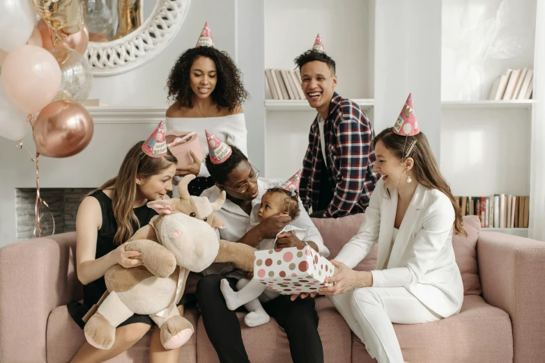 a group of people sitting on top of a couch, by Emma Andijewska, pexels contest winner, celebrating a birthday, giving gifts to people, with a kid, varying ethnicities