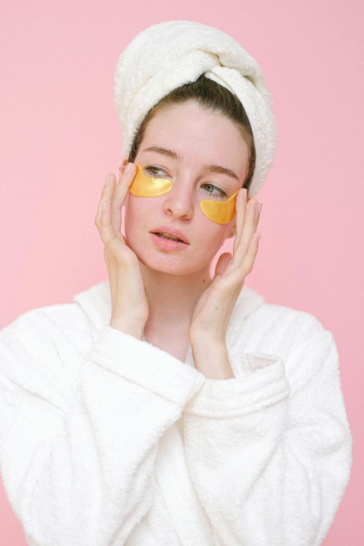 a woman in a bathrobe with orange slices on her face, an album cover, by Julia Pishtar, trending on pexels, eye patch, pink and gold, beautiful yellow woman, skin care