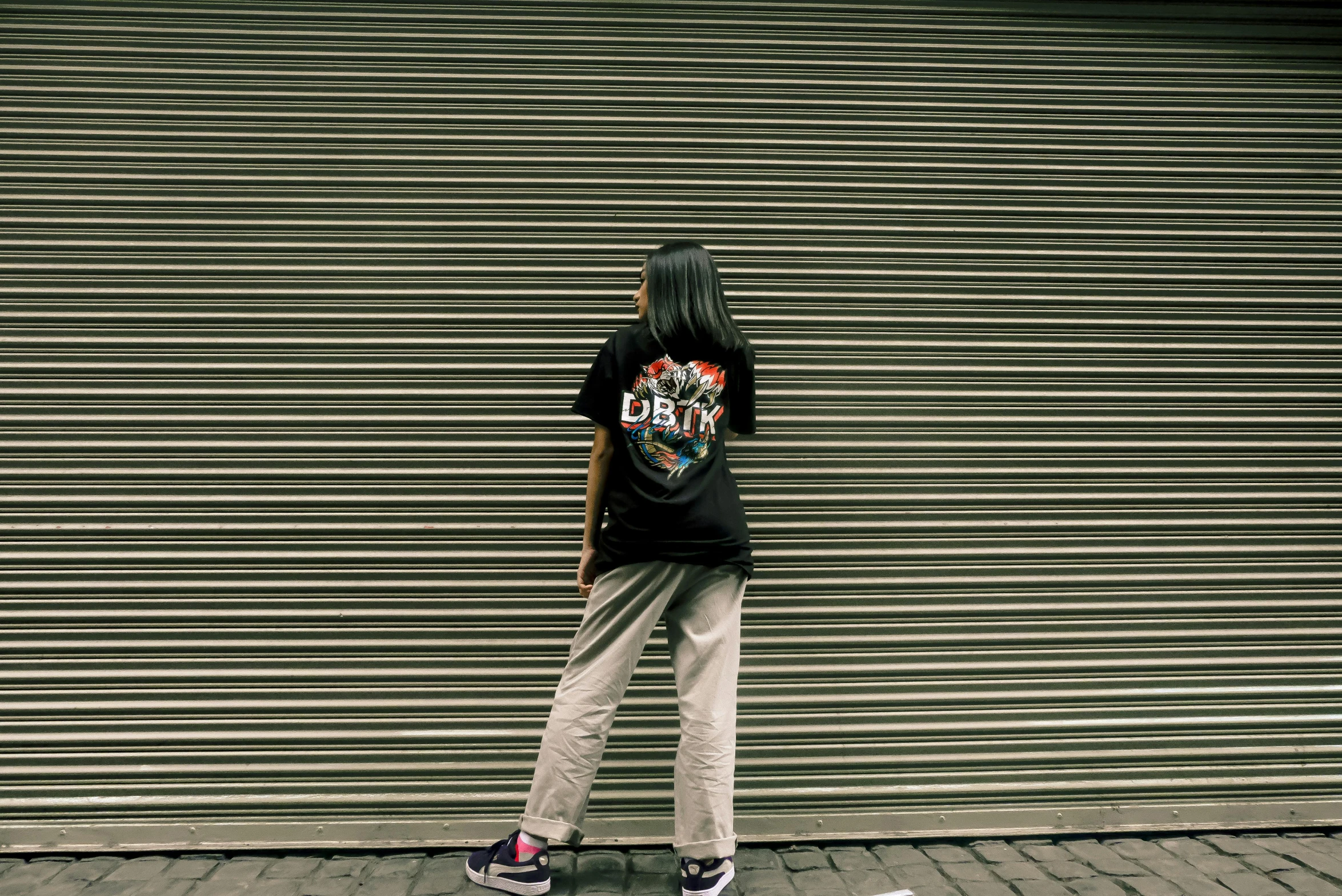 a person standing on a skateboard in front of a garage door, by Derf, japanese streetwear, dmt entity, ((((dirt brick road))))