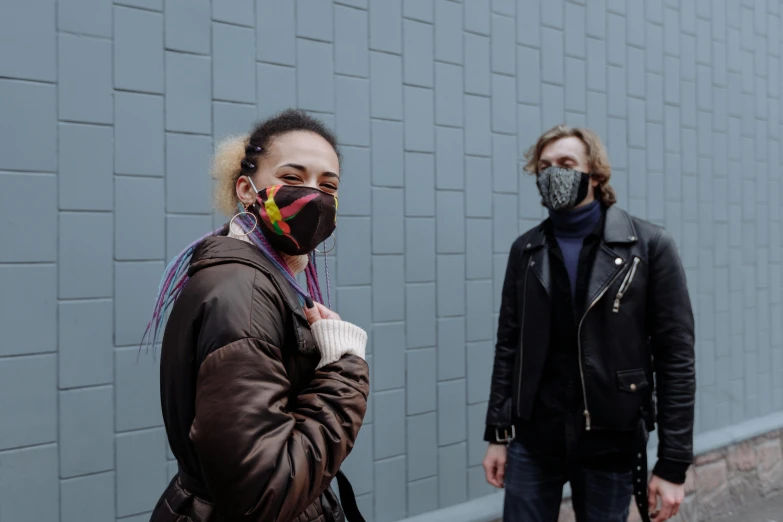 a woman standing next to a man wearing a face mask, by Nina Hamnett, pexels, antipodeans, wearing urban techwear, multi chromatic, cold weather, avatar image