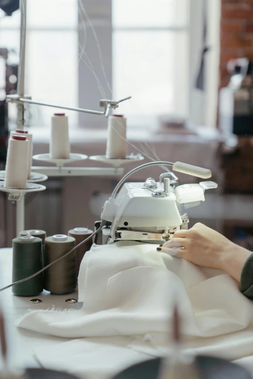 a woman is working on a sewing machine, a silk screen, trending on unsplash, ignant, controversial, white, construction