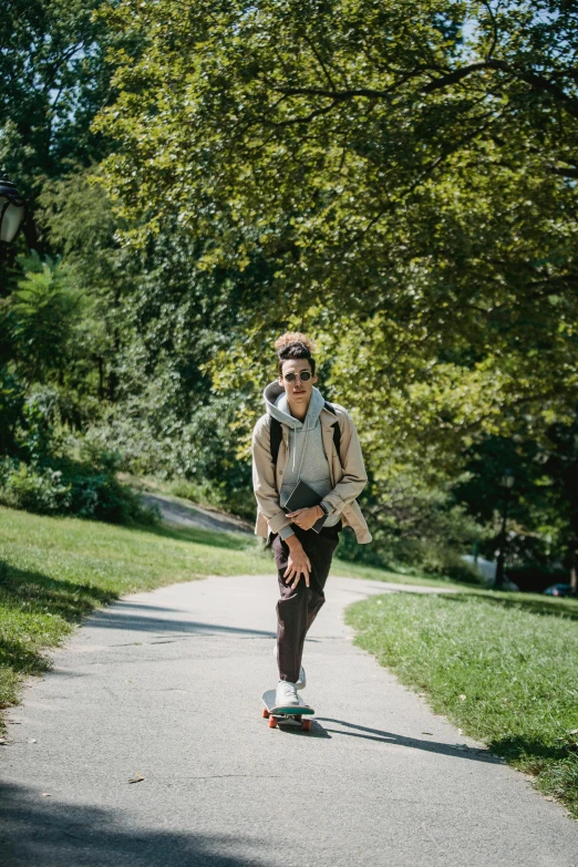a man riding a skateboard down a sidewalk, on a green hill, olmsted, with a backpack, julia sarda