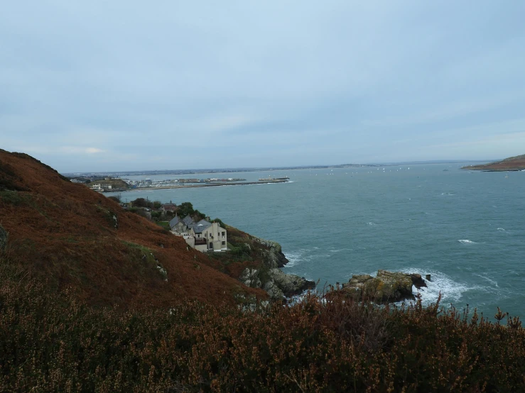 a man flying a kite on top of a lush green hillside, by Bascove, happening, rocky coast, grey, an overgrown, port