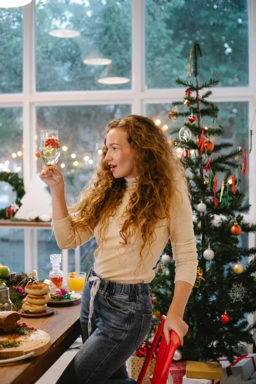 a woman sitting at a table with a glass of wine, pexels contest winner, christmas tree, standing, curly haired, gif