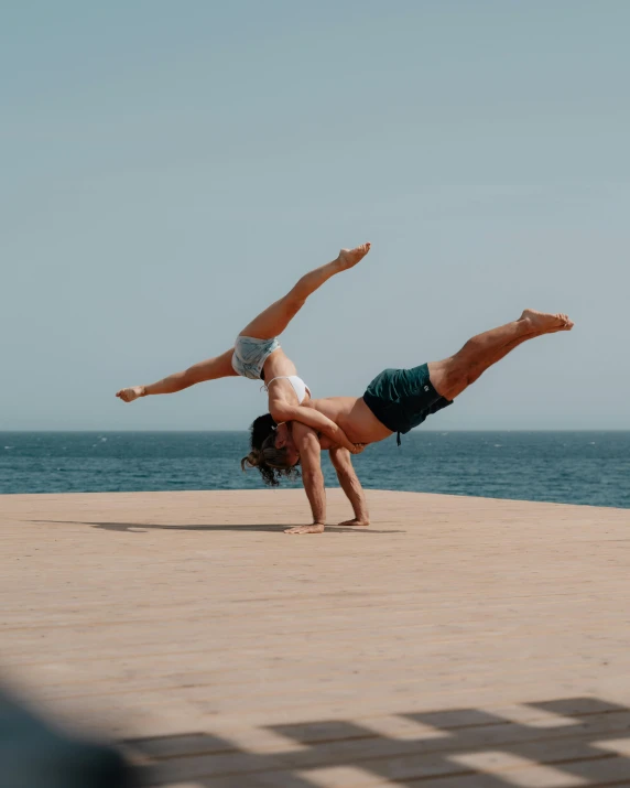 a woman doing a handstand in front of the ocean, pexels contest winner, arabesque, two muscular men entwined, on a hot australian day, an epic non - binary model, breakdancing