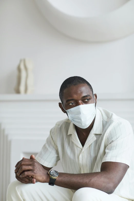 a man sitting on a couch wearing a face mask, visual art, black man, on a white table, hazy, (doctor)