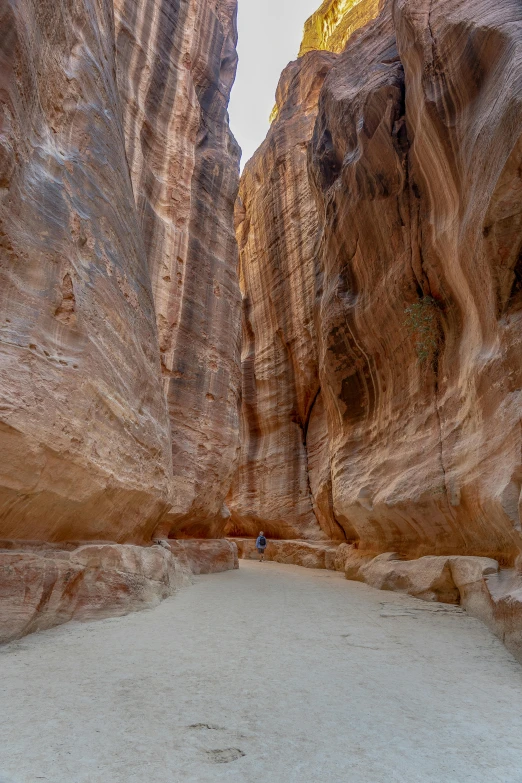 a group of people walking through a narrow canyon, by Peter Churcher, jordan, sandy beach, huge veins, street view