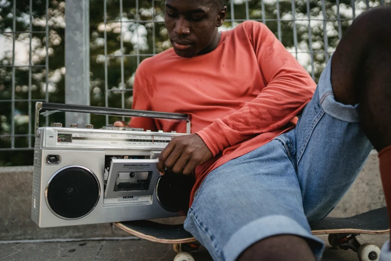 a man sitting on top of a skateboard next to a radio, trending on pexels, ghetto blaster, film still promotional image, close up portrait shot, ripped clothing