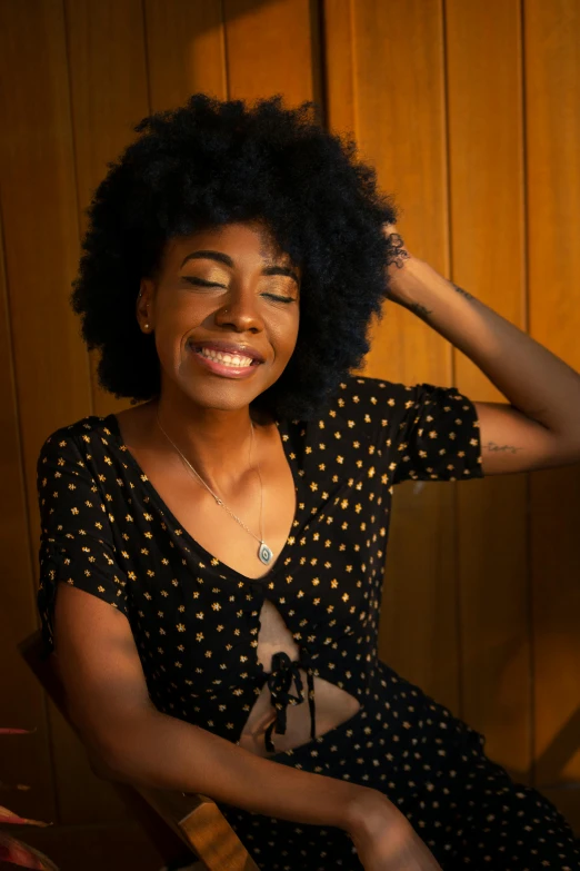 a woman sitting in a chair with a smile on her face, by Carey Morris, pexels contest winner, natural hair, sza, promo image, embracing