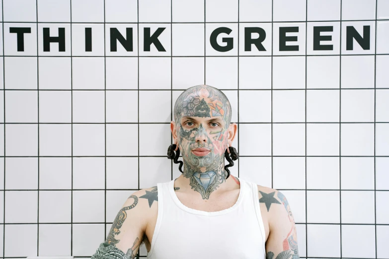 a man with tattoos standing in front of a sign, green and pink colour palette, daniel e. greene, pale grey skin, press photo