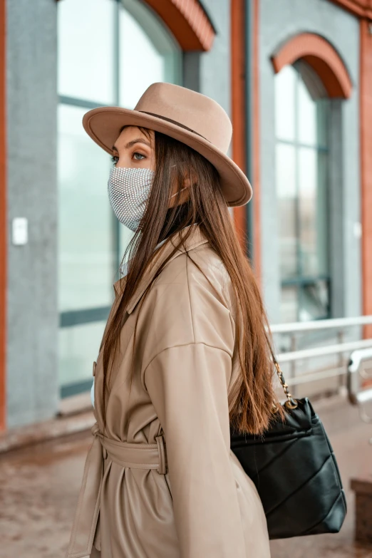 a woman wearing a face mask walking down the street, trending on pexels, renaissance, beige fedora, indoor picture, brown jacket, thumbnail