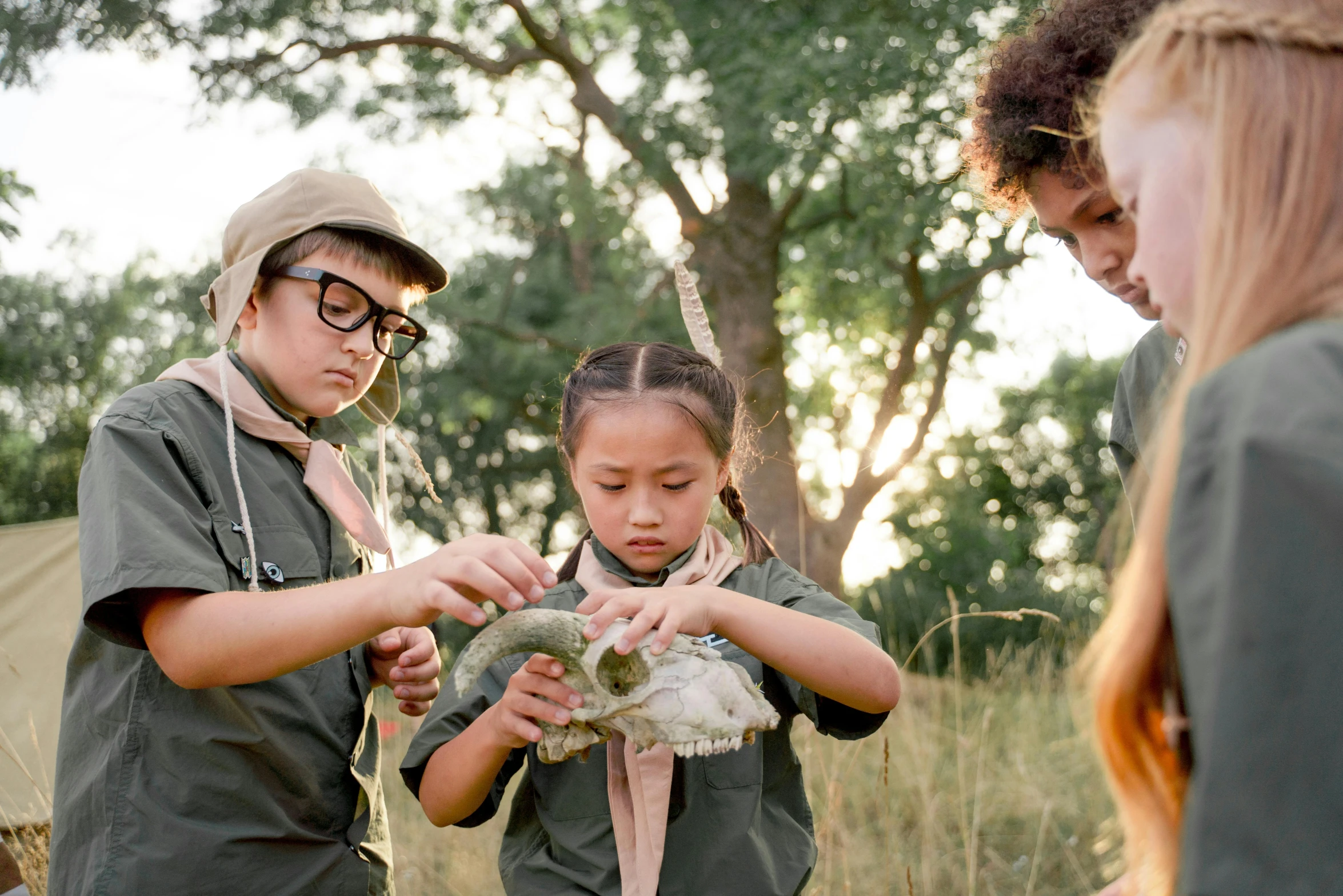 a group of children standing next to each other in a field, unsplash, visual art, with an animal skull for a head, explorer, holding a snake, weta workshop