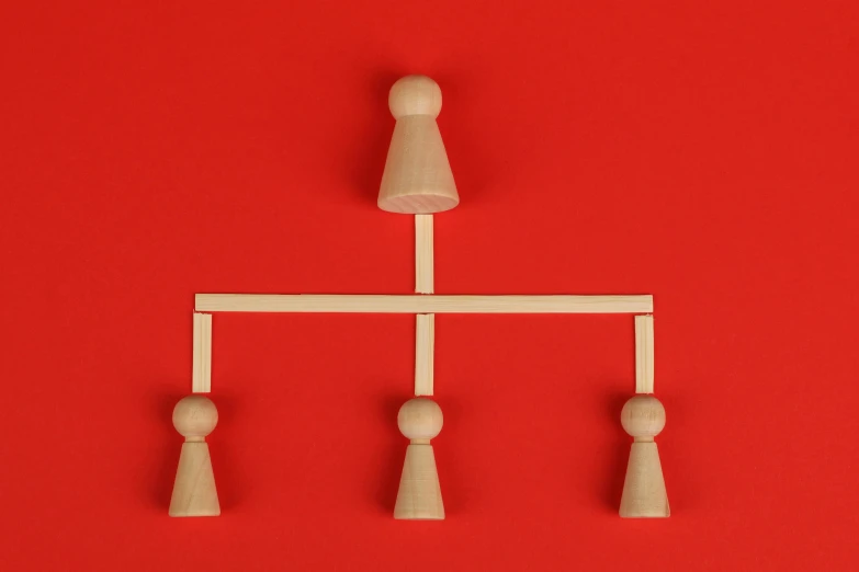 a close up of a wooden object on a red background, inspired by Oskar Schlemmer, unsplash, constructivism, as 3 figures, two hang, pyramid scheme, corporate boss