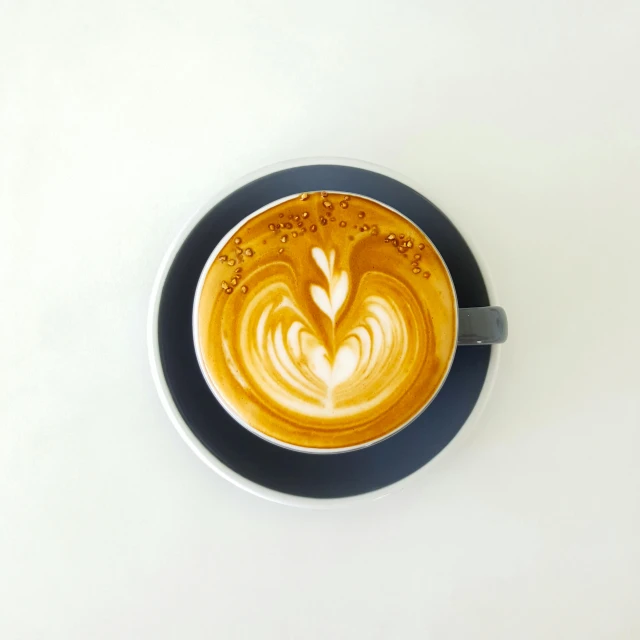 a cup of coffee sitting on top of a white table, symmetrical design, aussie baristas, blue, milk