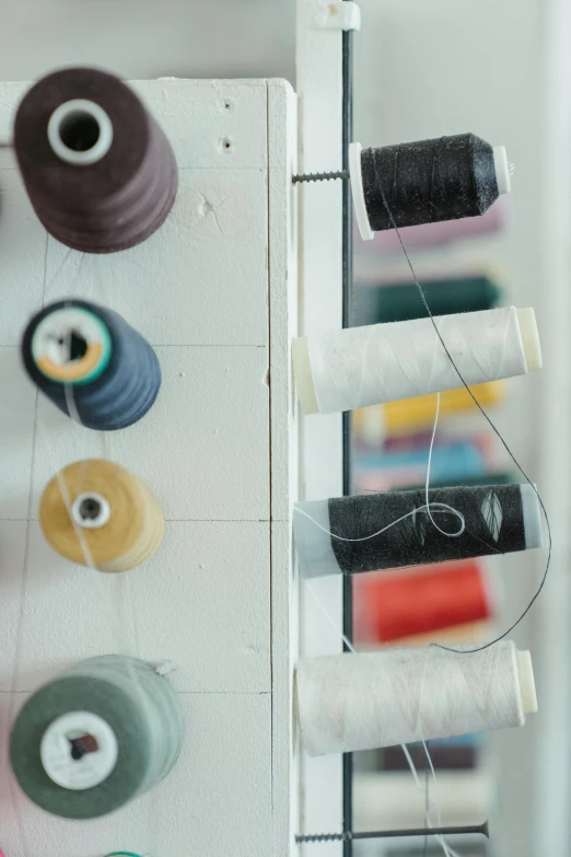 a close up of a bunch of spools of thread, a picture, by Jan Tengnagel, unsplash, white wall coloured workshop, hanging, multiple stories, fashion studio