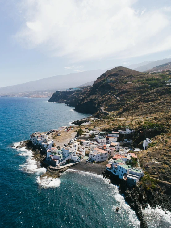 a large body of water next to a lush green hillside, by Daniel Lieske, pexels contest winner, happening, cliffside town, island in a blue sea, slide show, aerial footage