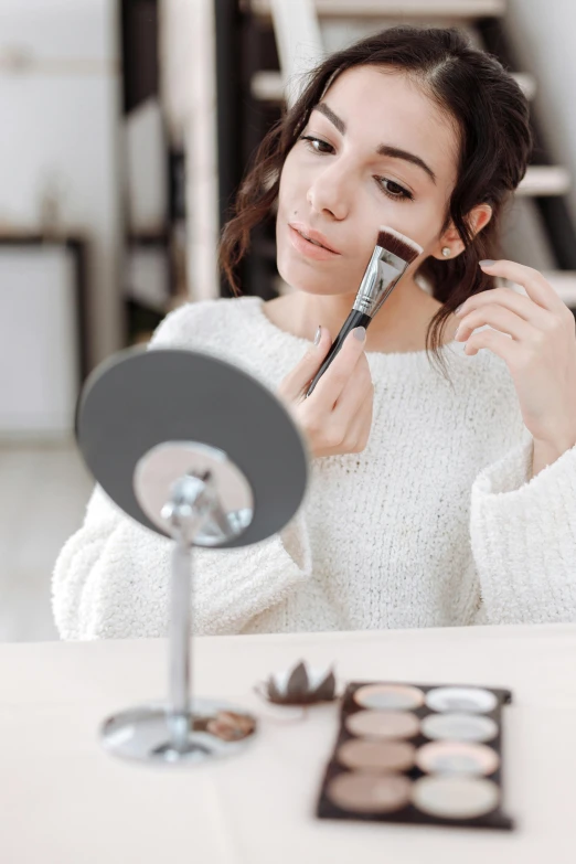 a woman is doing makeup in front of a mirror, textured base ; product photos, lean sleek styling, flat brush, trending on interfacelift