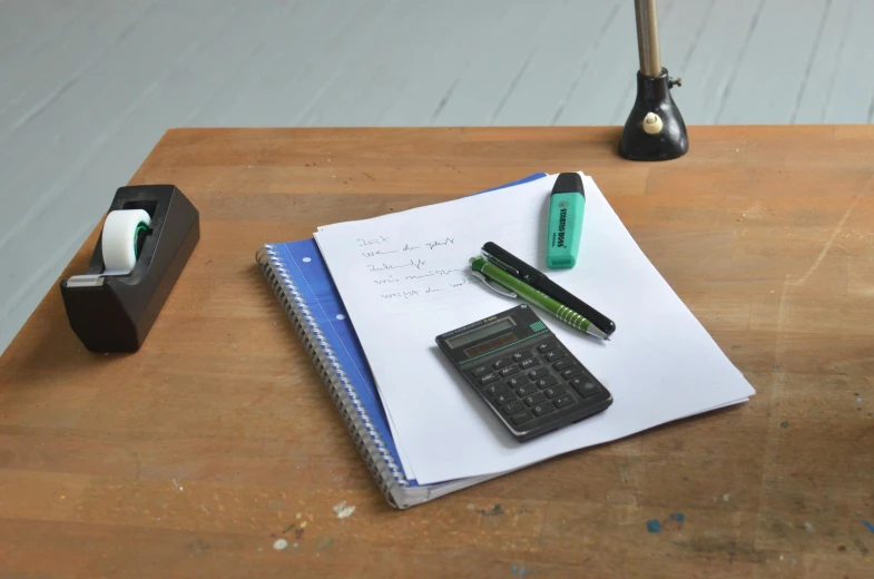 a desk with a calculator, pen, and notebook on it, an album cover, lined paper, whiteboard, medium - shot, felt tip pen