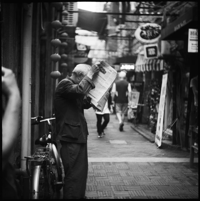 a black and white photo of a man reading a newspaper, a black and white photo, flickr, shin hanga, long street, 15081959 21121991 01012000 4k, unknown artist, posing for camera