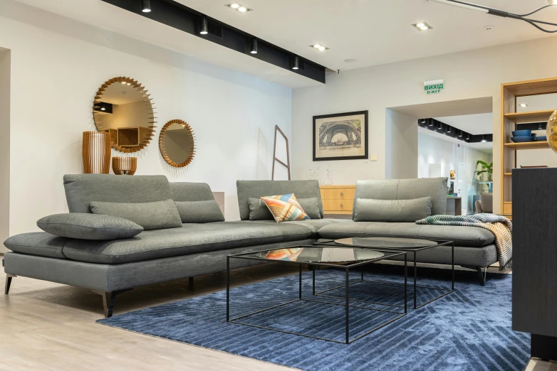 a living room filled with furniture and a blue rug, inspired by Emilio Grau Sala, unsplash, figuration libre, the store, esher, foster and partners, large couch