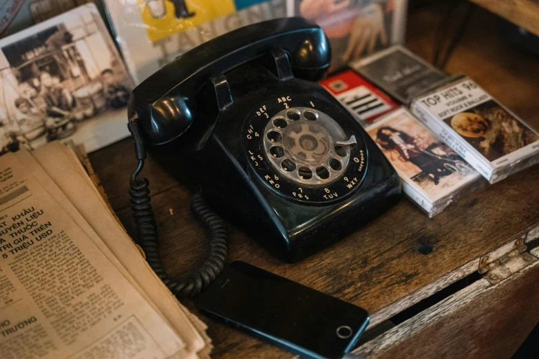 a black telephone sitting on top of a wooden table, by Joe Bowler, pexels contest winner, 🦩🪐🐞👩🏻🦳, 1 9 7 0 s, behind the scenes, dial