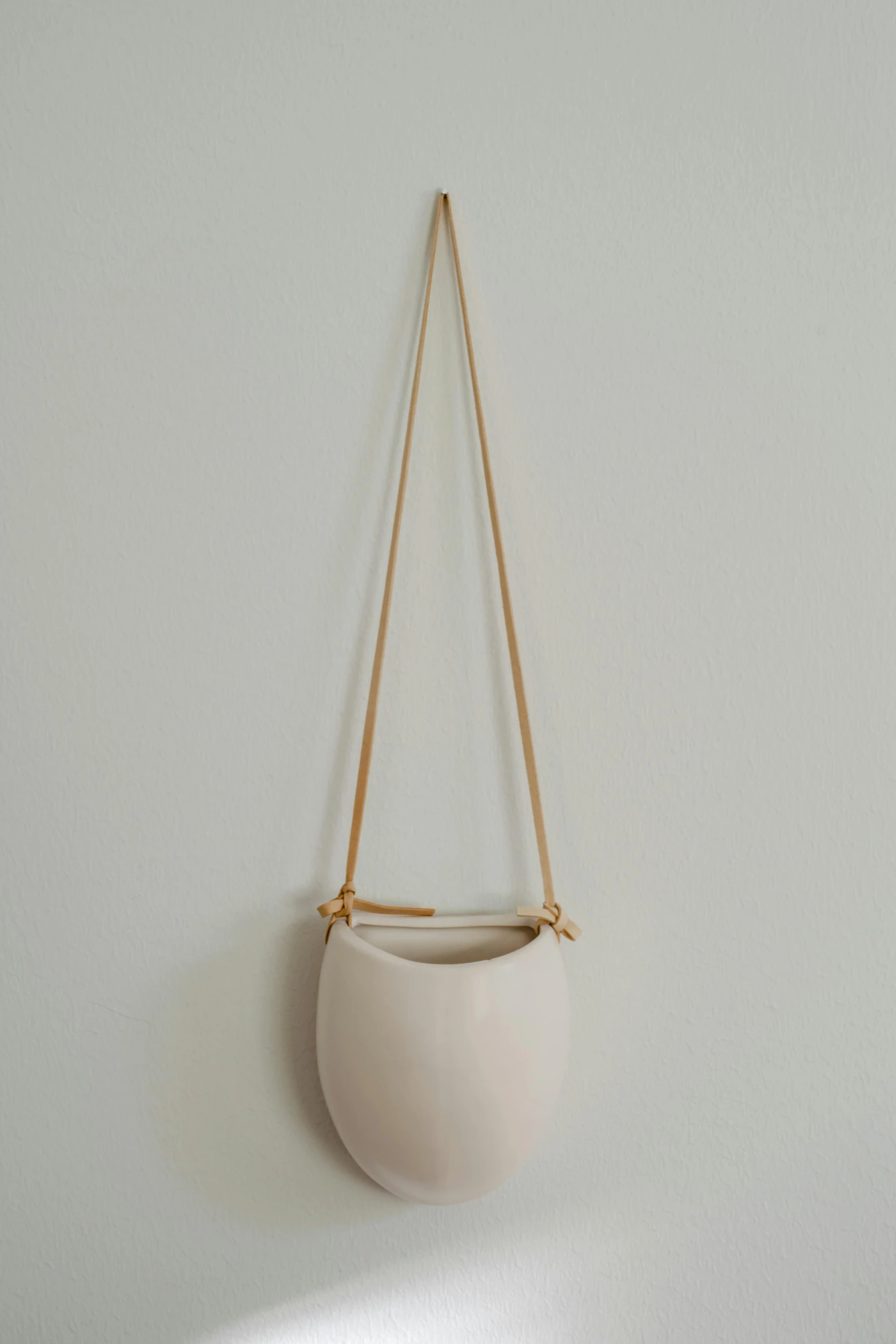 a close up of a hanging object on a wall, by Rebecca Horn, ceramic pot, bag, high resolution product photo, beige