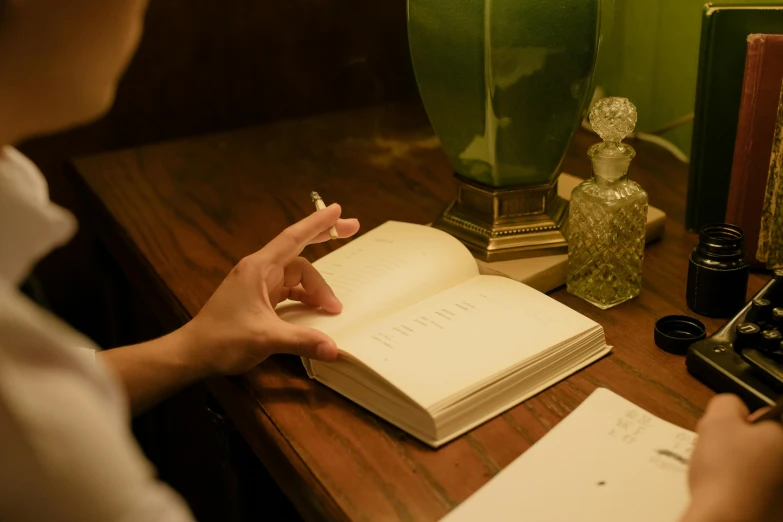 a person sitting at a desk writing on a book, private press, nightcap, spell book, ignant, trending photo