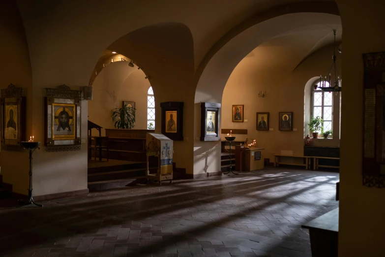 a room that has a bunch of paintings on the wall, by Eglon van der Neer, pexels, renaissance, in orthodox church, light coming from the entrance, brown, sweeping arches