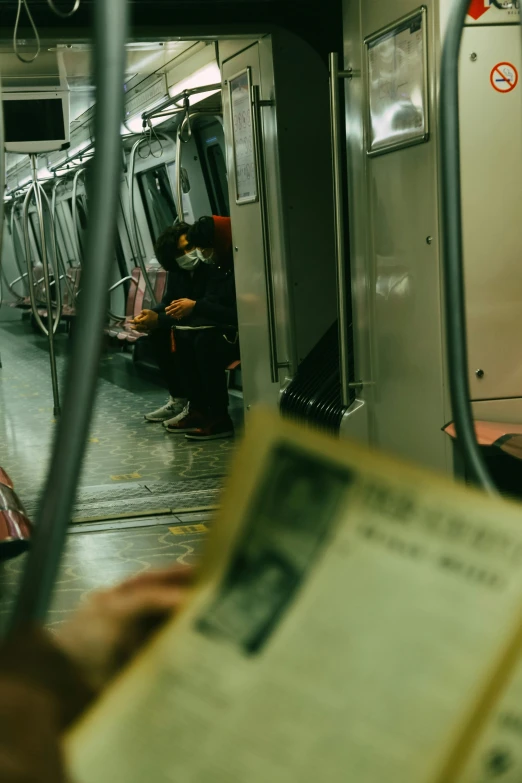 a person reading a book on a subway train, a picture, by William Berra, pexels contest winner, newspaper clippings, vintage color, 2 0 2 2 photo, npr