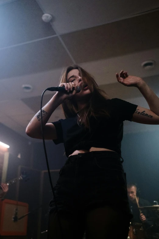 a woman on stage singing into a microphone, an album cover, pexels contest winner, antipodeans, boiler room, janis rozentals, 2019 trending photo, looking menacing