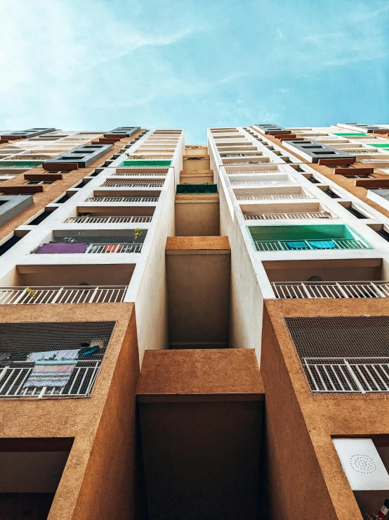 a tall building with lots of windows and a sky background, pexels contest winner, rows of doors, colorful caparisons, cascading highrise, concrete balcony