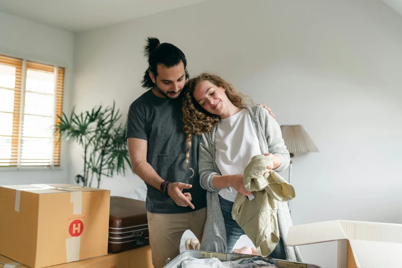 a man standing next to a woman in a room, pexels contest winner, happening, inspect in inventory image, happy couple, australian, belongings strewn about