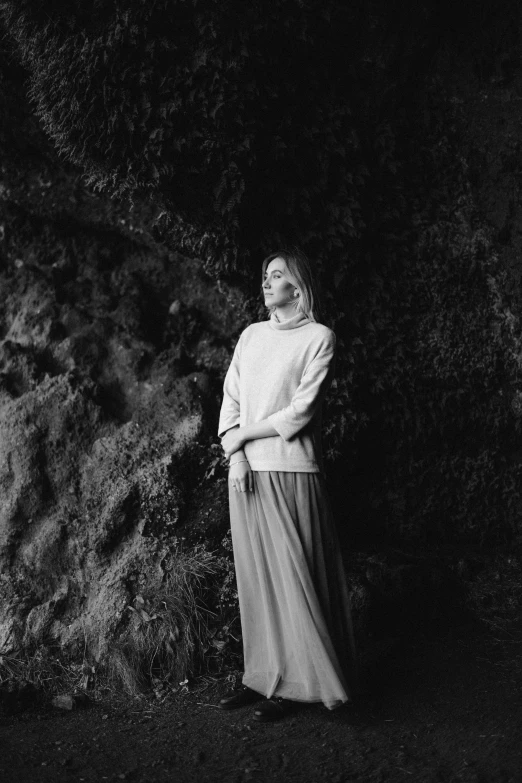 a black and white photo of a woman standing in front of a tree, unsplash, overgrown cave, long skirt, sydney sweeney, ((portrait))