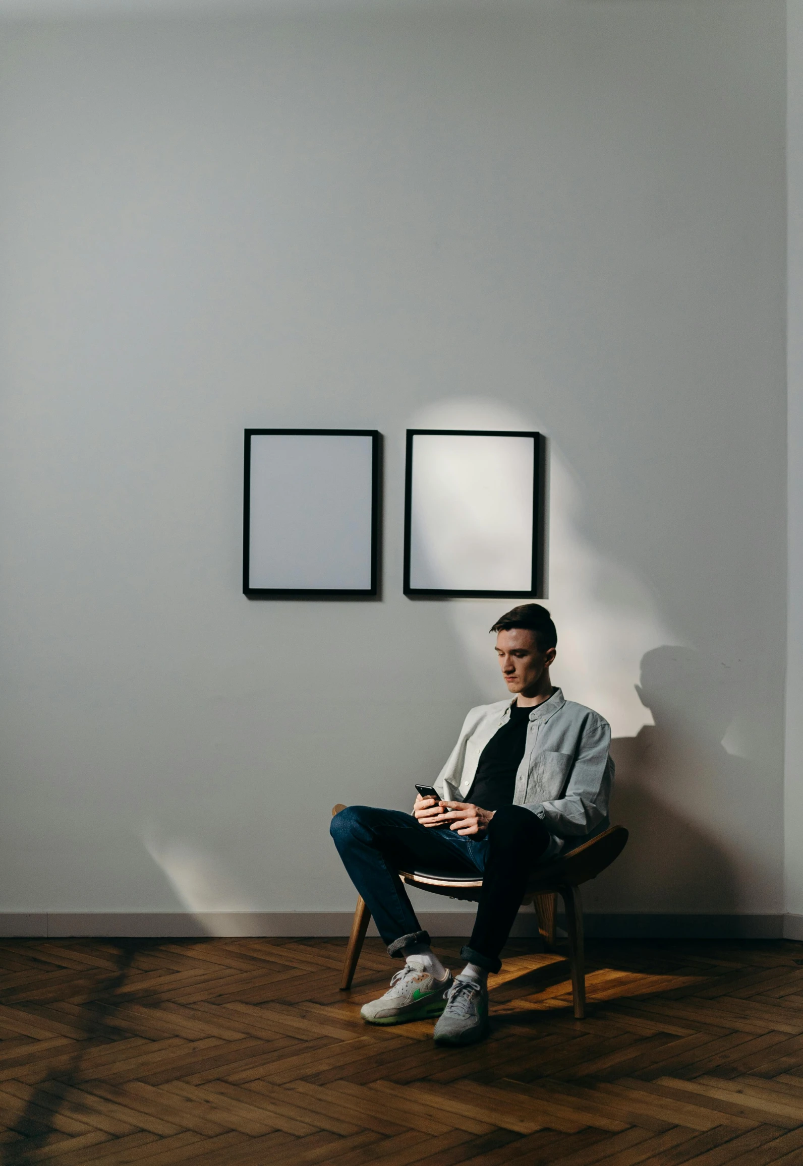 a man sitting in a chair in a room, a minimalist painting, trending on unsplash, visual art, looking at his phone, picture frames, thin young male, museum photograph