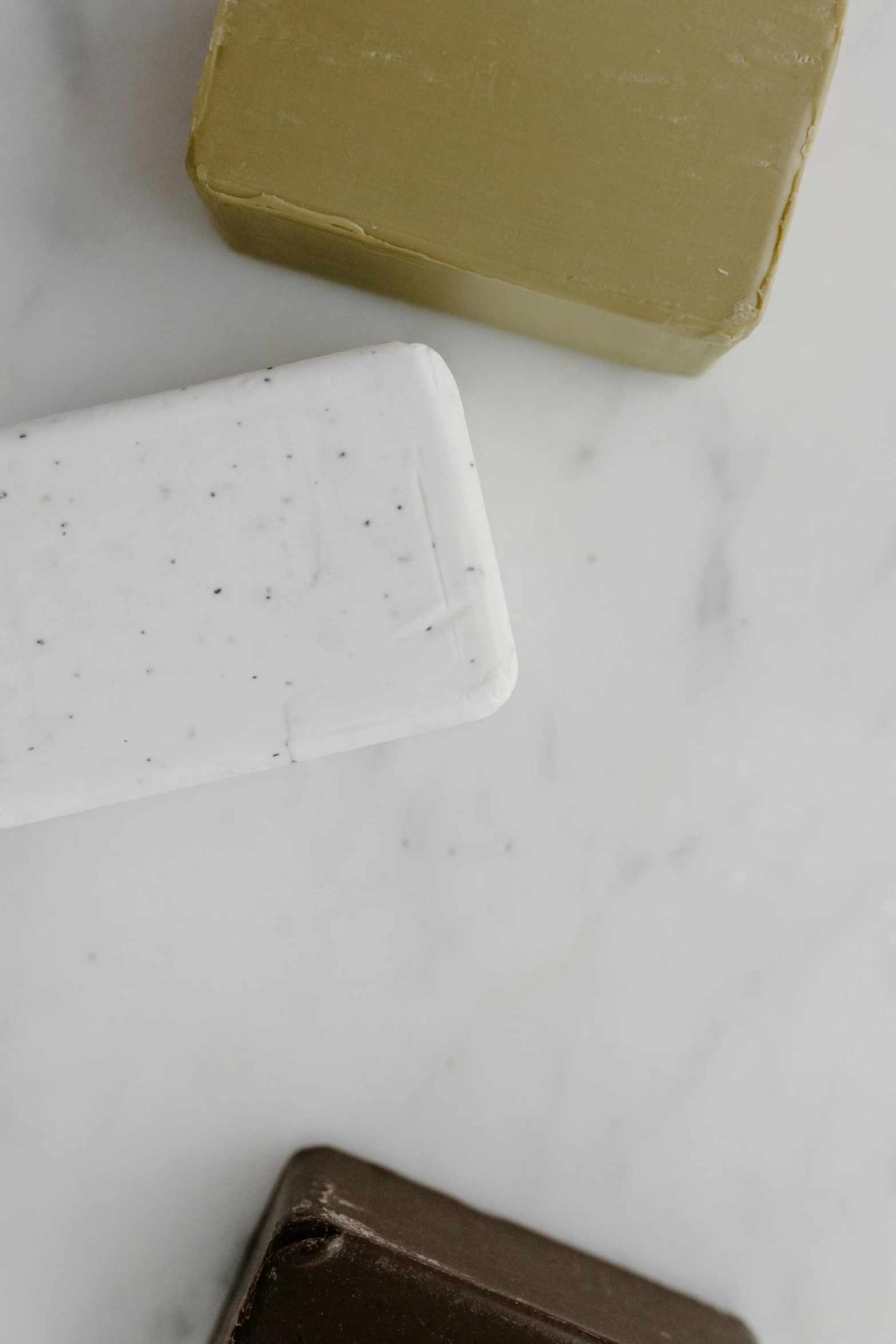 a couple of soap bars sitting on top of a counter, speckled, white clay, sparse detail, silicone cover
