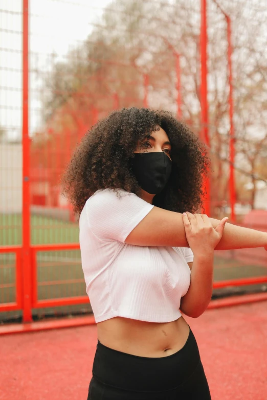 a woman holding a baseball bat on a baseball field, trending on pexels, afrofuturism, balaclava covering face, sports bra, afro, fencing