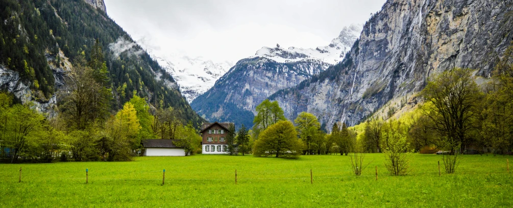 a house sitting on top of a lush green field, inspired by Karl Stauffer-Bern, pexels contest winner, icy mountains, classic beauty, festivals, commercially ready