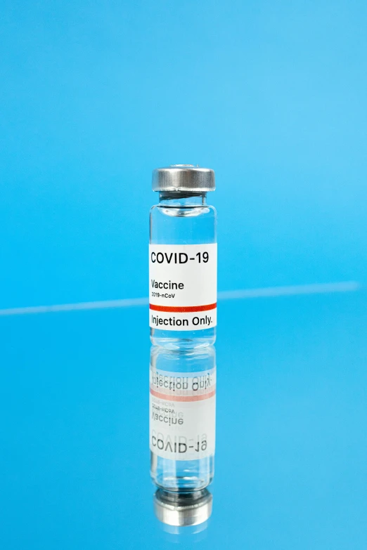 a vial filled with a vaccine sitting on top of a table, with a blue background, thumbnail, profile pic, label