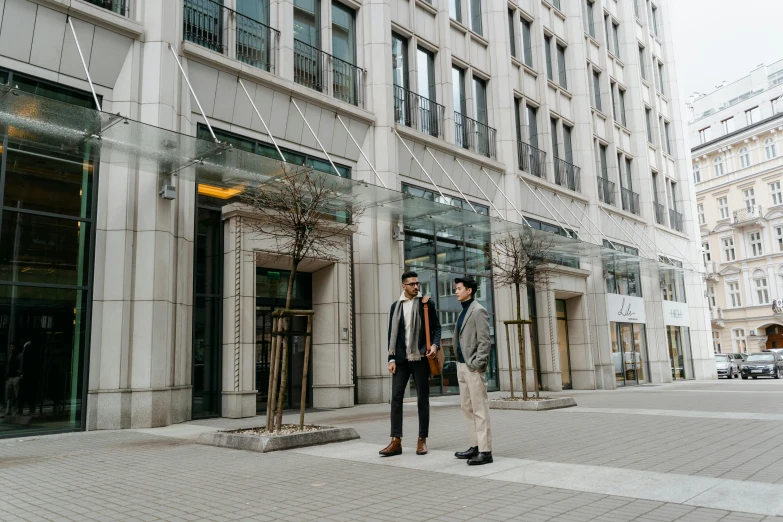 a couple of men standing in front of a building, pexels contest winner, downtown, thumbnail, calmly conversing 8k, tall entry