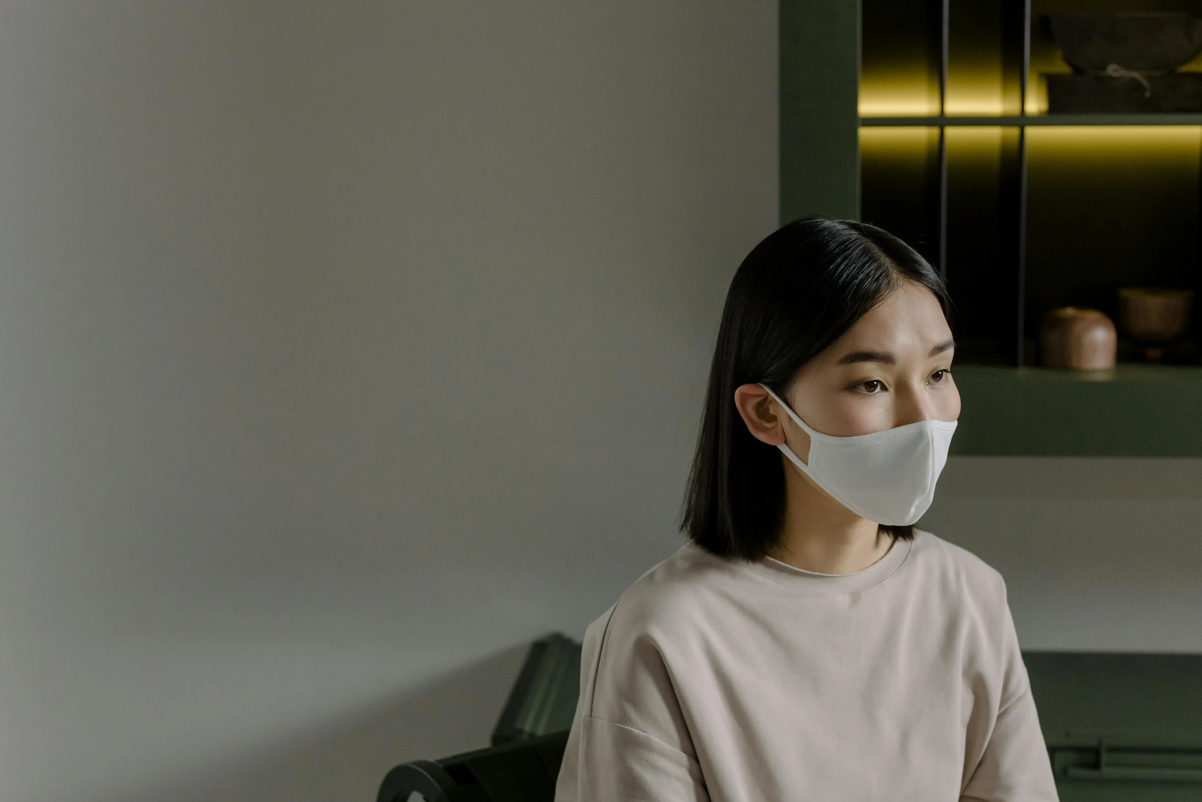 a woman sitting in a chair wearing a face mask, inspired by Fei Danxu, trending on pexels, looking away from the camera, minimalistic aesthetics, closed mouth, rectangle